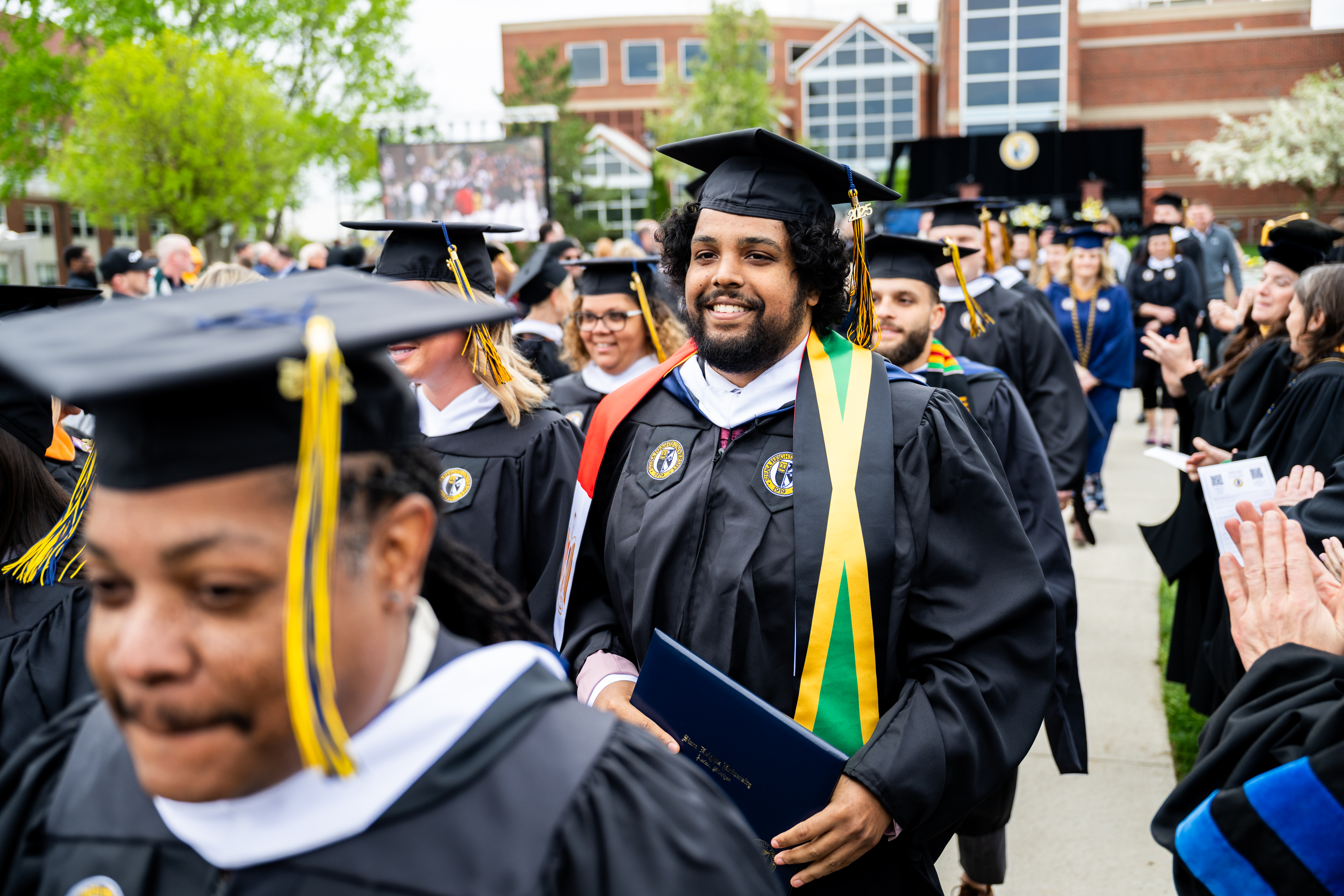 SHU Global 2025 Commencement. Masters degree graduate smiling.